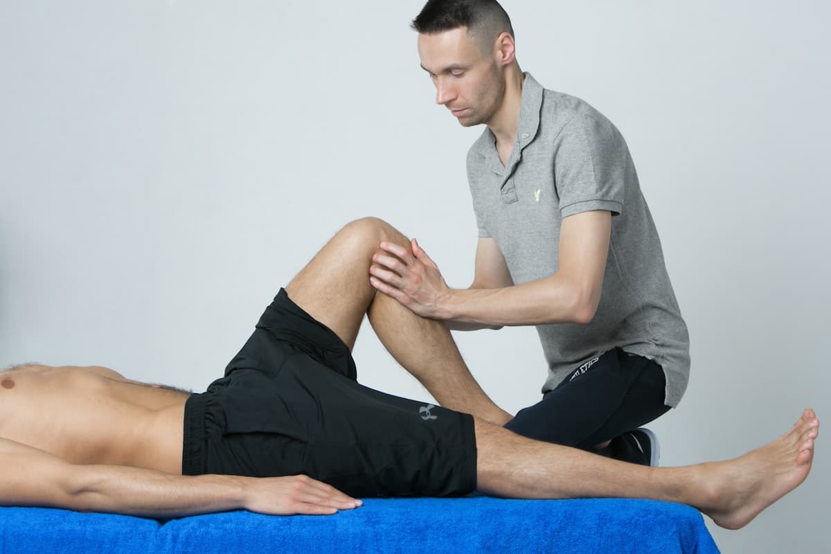 Practitioner performing applied kinesiology and joint mobilization on a patient's leg